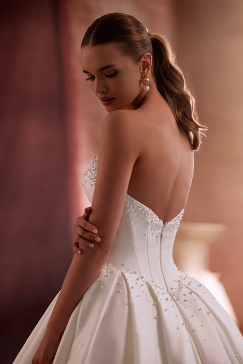 The Noor satin bridal gown with a voluminous skirt and sweeping train embodies royal elegance and refined style.