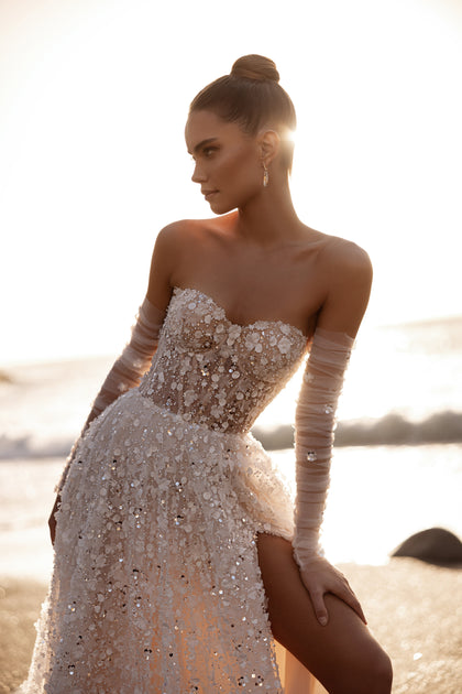 The Reem bridal gown featuring a structured bodice and thigh-high slit sparkles with intricate 3D embroidery under the evening sun.