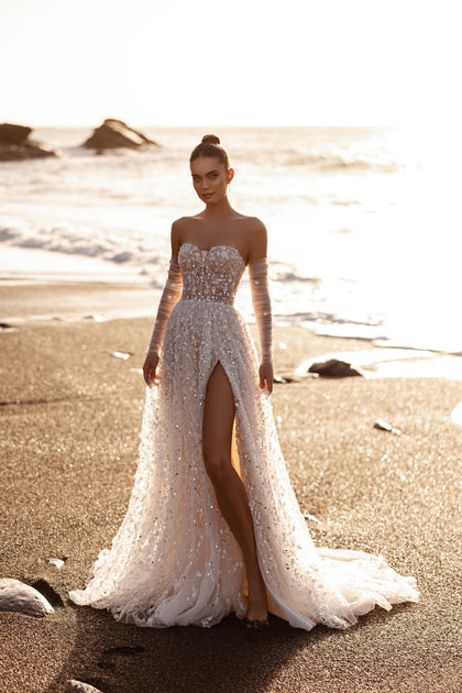 The Reem bridal dress featuring a sequined bodice and sweeping train glows with three-dimensional detail and coastal elegance.