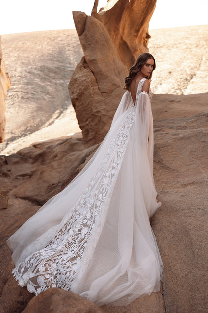 The Salome bridal dress featuring an ornate lace train and flowing silhouette showcases romantic boho sophistication.