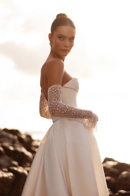 The Sarabi bridal gown featuring an open back and long train captures a balance of simplicity and sophistication.