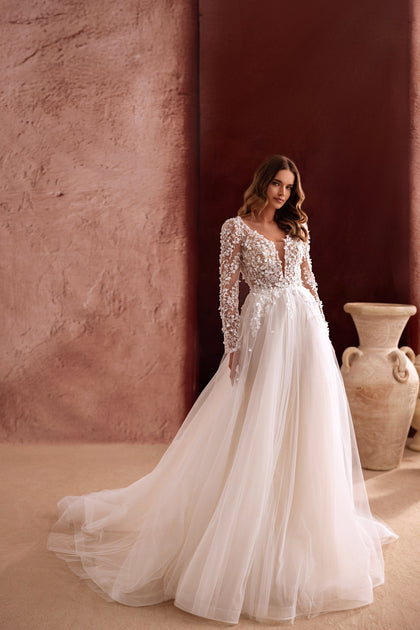 The Shanin bridal gown featuring lace long sleeves, plunging neckline, and airy tulle skirt captures timeless sophistication.