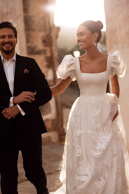 The Vanilla bridal gown with sheer organza sleeves and floral embroidery embodies romantic elegance.