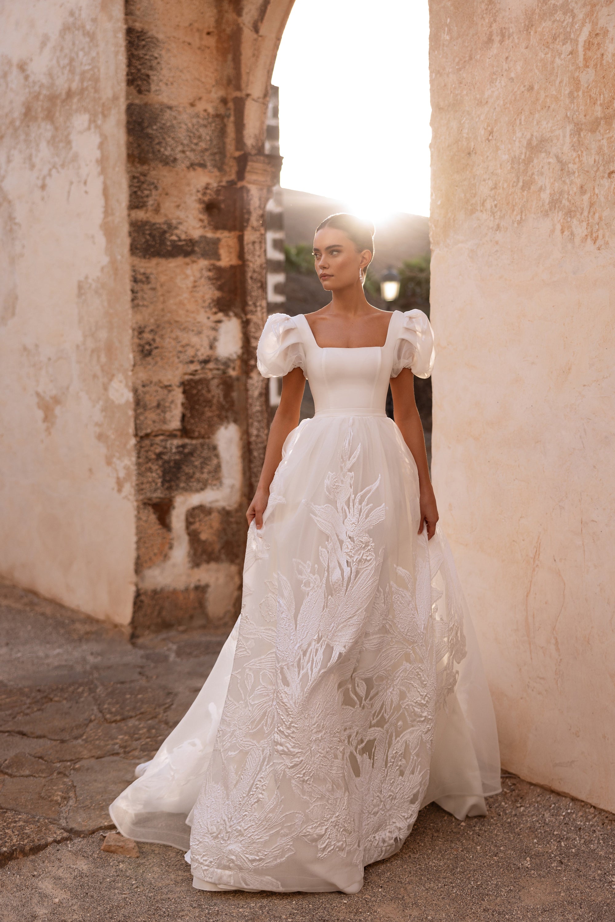 The Vanilla wedding dress with square neckline and puff sleeves captures a joyful bridal moment.