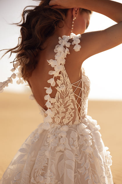 The Wisteria bridal gown with delicate floral straps and deep neckline radiates elegance in the desert light.