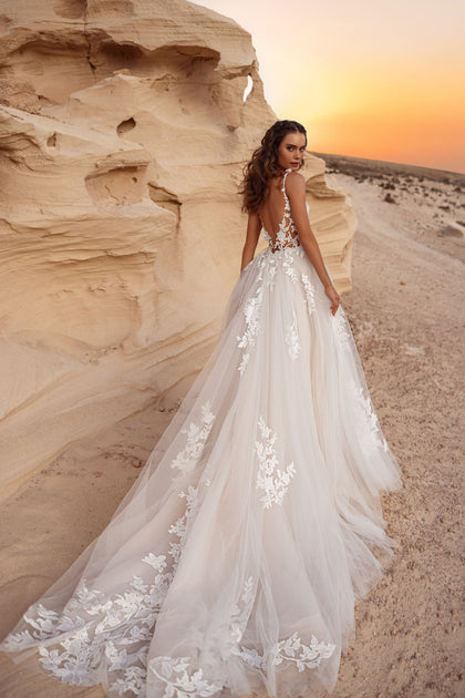The Zafira bridal gown with an open back and extended tulle train featuring intricate 3D lace appliqué.