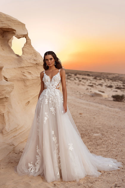 The Zafira bridal gown with a deep V-neckline and delicate 3D lace appliqué stands out in the soft desert sunset.